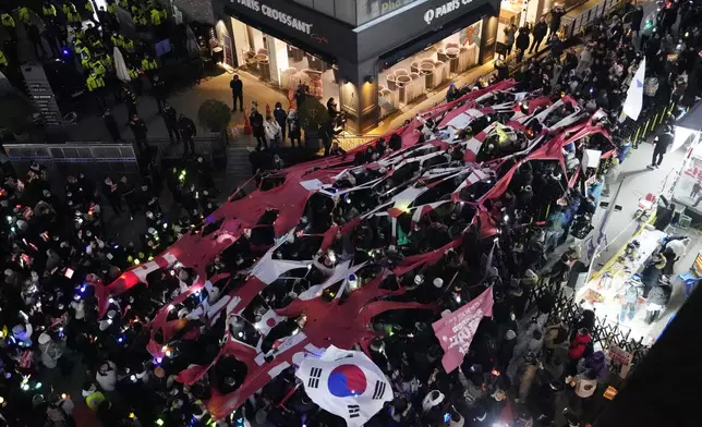 Participants tear a banner representing the flag of the ruling People Power Party during a rally to demand South Korean President Yoon Suk Yeol's impeachment in front of the headquarters of the ruling People Power Party, in Seoul, South Korea, Monday, Dec. 9, 2024. (AP Photo/Ahnn Young-joon)