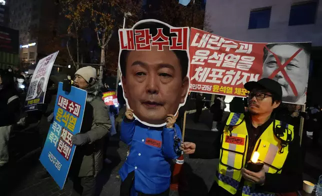 A participant wearing a mask of South Korean President Yoon Suk Yeol attends a rally demanding his impeachment outside the National Assembly in Seoul, South Korea, Sunday, Dec. 8, 2024.The signs read "Arrest Yoon Suk Yeol." (AP Photo/Ahn Young-joon)