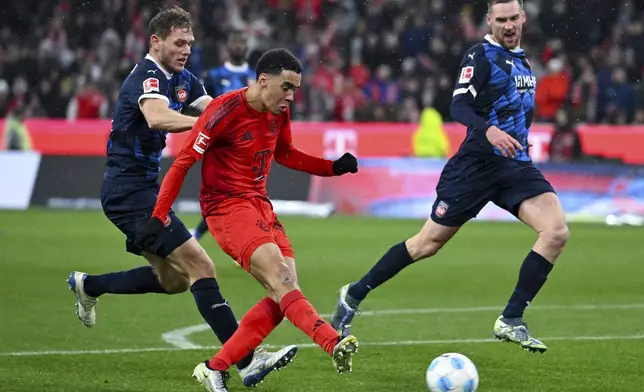 Munich's Jamal Musiala, front, scores his side's fourth goal during the German Bundesliga soccer match between FC Bayern Munich and 1. FC Heidenheim 1846 in Munich, Germany, Saturday, Dec. 7, 2024. (Sven Hoppe/dpa via AP)