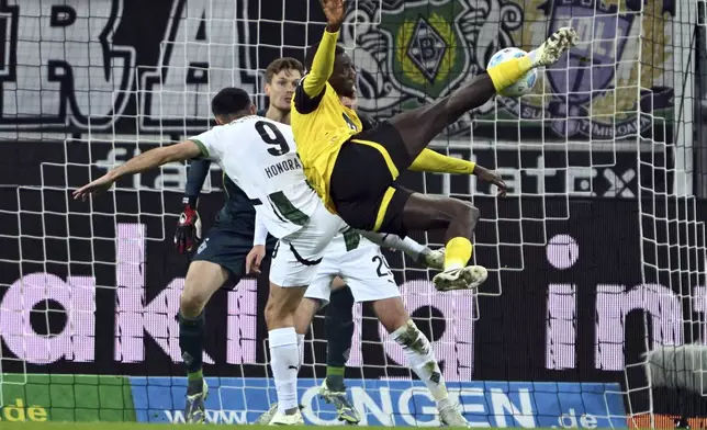 Borussia Mönchengladbach's Franck Honorat (9) and Borussia Dortmund's Sehrou Guirassy fight for the ball during a Bundesliga soccer match, Saturday, Dec. 7, 2025, in Mönchengladbach, Germany. (Federico Gambarini/dpa via AP)