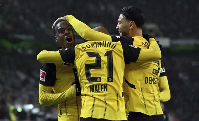 Borussia Dortmund's Jamie Gittens, left, celebrates with Donyell Malen (21) and Ramy Bensebaini after scoring a goal against Borussia Mönchengladbach during a Bundesliga soccer match, Saturday, Dec. 7, 2025, in Mönchengladbach, Germany. (Federico Gambarini/dpa via AP)