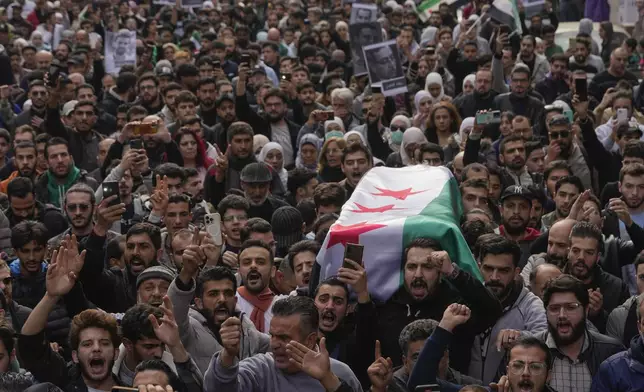 The coffin of Syrian activist Mazen al-Hamada is carried for burial in Damascus Thursday Dec. 12, 2024. Al-Hamad's mangled corpse was found wrapped in a bloody sheet in Saydnaya prison. He had fled to Europe but returned to Syria in 2020 and was imprisoned upon arrival. (AP Photo/Hussein Malla)