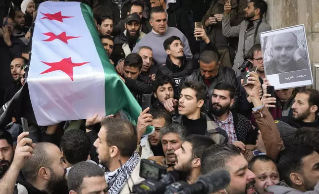 The coffin of Syrian activist Mazen al-Hamada is carried for burial in Damascus Thursday Dec. 12, 2024. Al-Hamad's mangled corpse was found wrapped in a bloody sheet in Saydnaya prison. He had fled to Europe but returned to Syria in 2020 and was imprisoned upon arrival. (AP Photo/Hussein Malla)