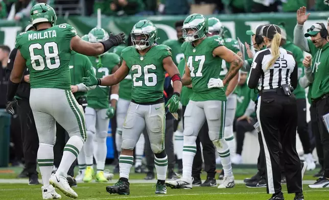 Philadelphia Eagles running back Saquon Barkley (26) is congratulated by offensive tackle Jordan Mailata and teammates after running for a long gain to put him at over 2,000 yards for the season during the second half of an NFL football game against the Dallas Cowboys, Sunday, Dec. 29, 2024, in Philadelphia. (AP Photo/Chris Szagola)