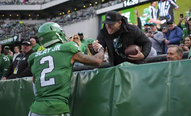 Philadelphia Eagles cornerback Darius Slay Jr. (2) gifts the football to Los Angeles Angels baseball outfielder Mike Trout after recovering a fumble by Dallas Cowboys running back Rico Dowdle during the second half of an NFL football game, Sunday, Dec. 29, 2024, in Philadelphia. (AP Photo/Matt Slocum)