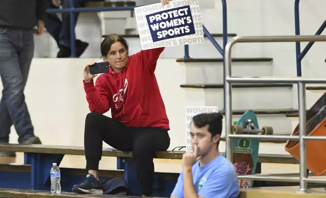 A spectator holds up a Protect Women's Sports sign during the third set of an NCAA college volleyball match between the San Jose State Spartans and the Air Force Falcons Thursday, Oct. 31, 2024, in San Jose, Calif. (AP Photo/Eakin Howard)