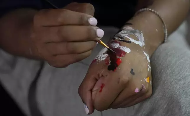 California basketball player Jayda Noble mixes paint on her hand while painting shoes in Berkeley, Calif., Monday, Oct. 21, 2024. (AP Photo/Jeff Chiu)