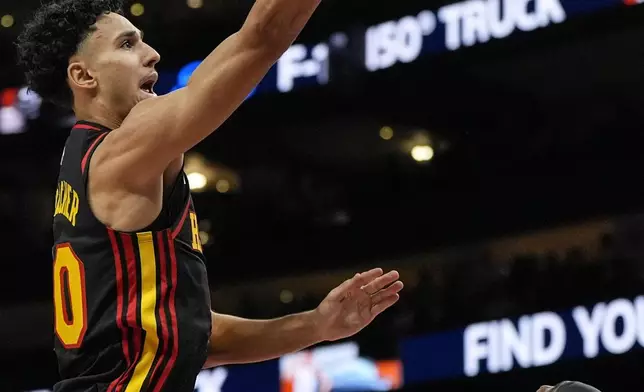 Atlanta Hawks forward Zaccharie Risacher (10) shoots against Atlanta Hawks guard Bogdan Bogdanovic (13) during the first half of an NBA basketball game, Saturday, Dec. 28, 2024, in Atlanta. (AP Photo/Mike Stewart)