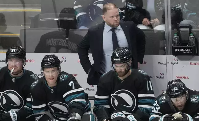 San Jose Sharks head coach Ryan Warsofsky, standing, watches from the bench during the third period of an NHL hockey game against the Colorado Avalanche in San Jose, Calif., Thursday, Dec. 19, 2024. (AP Photo/Jeff Chiu)