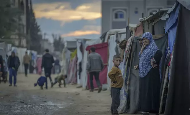 Palestinians stand outside their tents at a camp for displaced people in Deir al-Balah, Gaza Strip, Thursday, Dec. 12, 2024. (AP Photo/Abdel Kareem Hana)