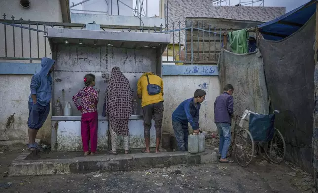 Palestinian children collect water in jerrycans at a camp for displaced people in Deir al-Balah, Gaza Strip, Thursday, Dec. 12, 2024. (AP Photo/Abdel Kareem Hana)