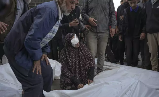 Isra Al Habash, mourns her father and brothers, victims of an Israeli army strike on the Nuseirat refugee camp, at the Al-Aqsa Martyrs hospital in Deir al-Balah, Gaza Strip, Thursday Dec. 12, 2024. Palestinian medical officials say Israeli airstrikes have killed at least 28 people in the Gaza Strip, including seven children and a woman. (AP Photo/Abdel Kareem Hana)