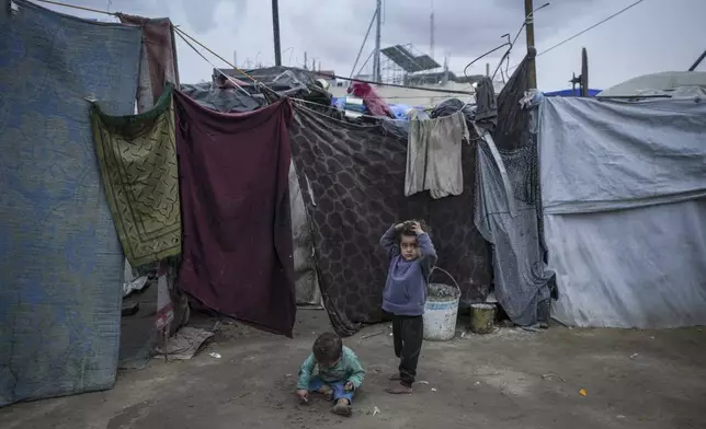 Palestinian children play on the dirt next to the tents of a camp for displaced people in Deir al-Balah, Gaza Strip, on Thursday, Dec. 12, 2024. (AP Photo/Abdel Kareem Hana)