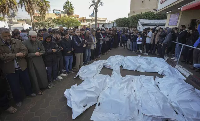 Palestinians pray over the civilian victims of an Israeli army strike on the Nuseirat refugee camp, at the Al-Aqsa Martyrs hospital in Deir al-Balah, Gaza Strip, Thursday Dec. 12, 2024. Palestinian medical officials say Israeli airstrikes have killed at least 28 people in the Gaza Strip, including seven children and a woman. (AP Photo/Abdel Kareem Hana)