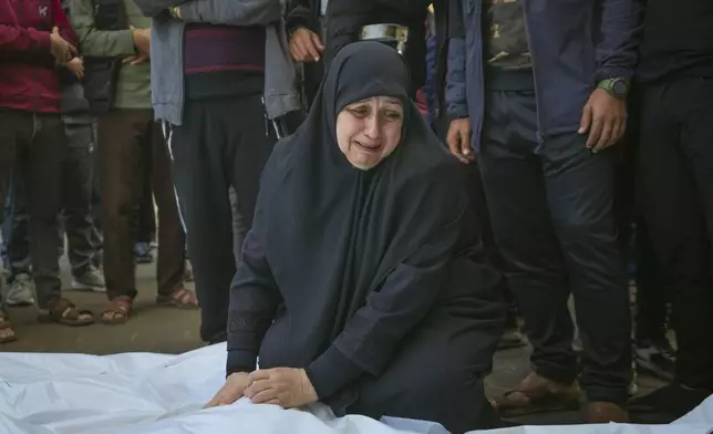 Asma Al Habash, mourns her brother and his family, victims of an Israeli army strike on the Nuseirat refugee camp, at the Al-Aqsa Martyrs hospital in Deir al-Balah, Gaza Strip, Thursday Dec. 12, 2024. Palestinian medical officials say Israeli airstrikes have killed at least 28 people in the Gaza Strip, including seven children and a woman. (AP Photo/Abdel Kareem Hana)