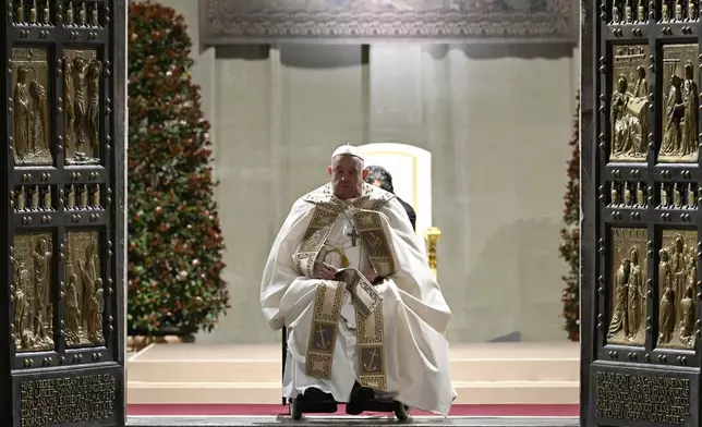 In this image released by Vatican Media, Pope Francis opens the holy door marking the start of the Catholic jubilar year 2025 before presiding over the Christmas Eve Mass in St. Peter's Basilica at The Vatican, Tuesday, Dec. 24, 2024. (AP Photo/Vatican Media, HO)