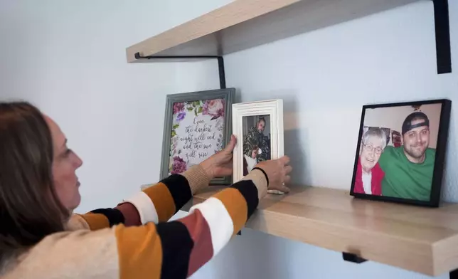 Jen Dold, whose brother, Alex Dold, lived with schizophrenia and died after a 2017 encounter with sheriff's deputies and police officers, adjusts one of her favorite photos of her brother on her living room shelf at her home Wednesday, Sept. 18, 2024, in Edmonds, Wash. (AP Photo/Lindsey Wasson)