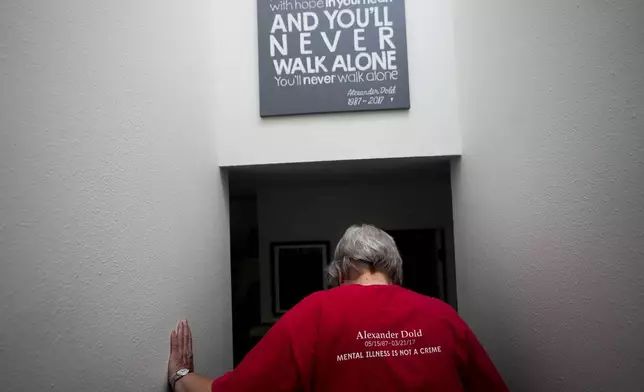 Kathy Duncan, whose son, Alex Dold, lived with schizophrenia and died after a 2017 encounter with sheriff's deputies and police officers, walks down stairs past a piece of art made for her son at the house of her daughter, Jen Dold, Wednesday, Sept. 18, 2024, in Edmonds, Wash. (AP Photo/Lindsey Wasson)