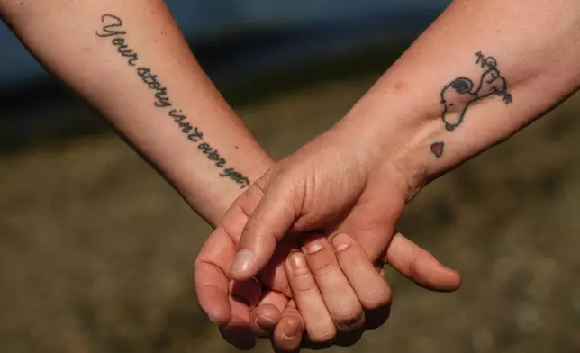 Jen Dold, left, and her mother, Kathy Duncan, right, display tattoos they got in honor of their brother and son, Alex Dold, who lived with schizophrenia and died after a 2017 encounter with sheriff's deputies and police officers, Wednesday, Sept. 18, 2024, at a beach in Edmonds, Wash. (AP Photo/Lindsey Wasson)