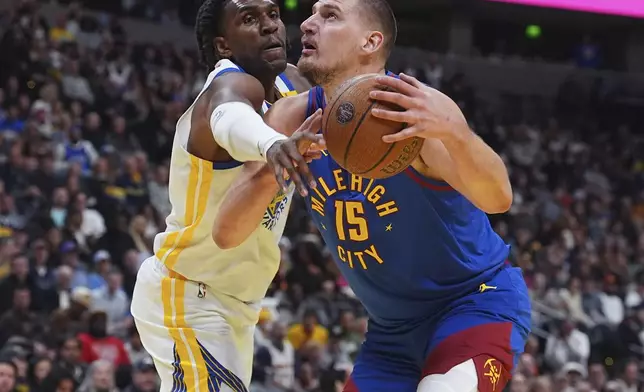 Golden State Warriors forward Kevon Looney, left, knocks the ball out of the hands of Denver Nuggets center Nikola Jokic as he drives to the rim in the first half of an Emirates NBA Cup basketball game Tuesday, Dec. 3, 2024, in Denver. (AP Photo/David Zalubowski)