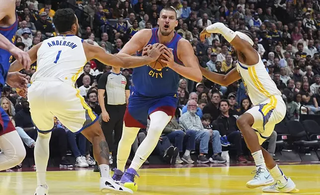 Denver Nuggets center Nikola Jokic, center, drives between Golden State Warriors forward Kyle Anderson, left, and guard Moses Moody in the first half of an Emirates NBA Cup basketball game Tuesday, Dec. 3, 2024, in Denver. (AP Photo/David Zalubowski)