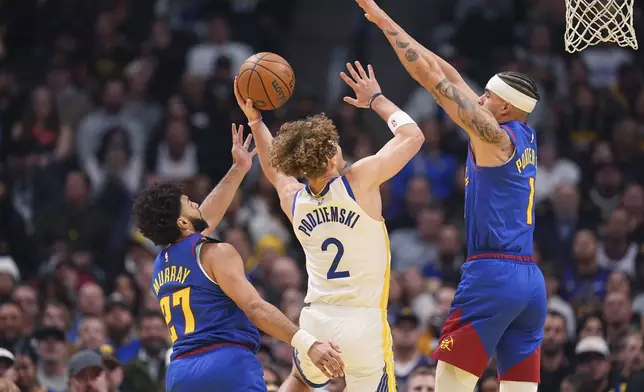 Golden State Warriors guard Brandin Podziemski, center, goes up for a basket between Denver Nuggets guard Jamal Murray and forward Michael Porter Jr. in the first half of an Emirates NBA Cup basketball game Tuesday, Dec. 3, 2024, in Denver. (AP Photo/David Zalubowski)