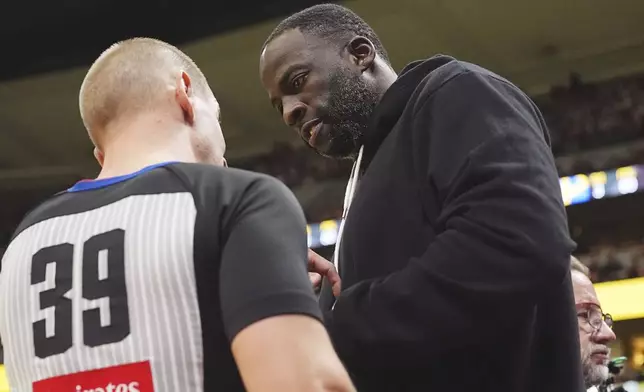 Referee Tyler Ford, left, confers with Golden State Warriors forward Draymond Green during a time out in the first half of an Emirates NBA Cup basketball game against the Denver Nuggets Tuesday, Dec. 3, 2024, in Denver. (AP Photo/David Zalubowski)