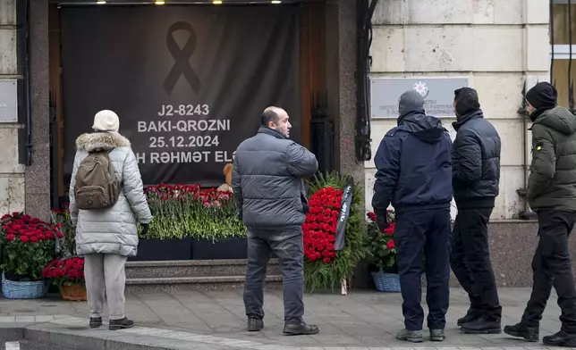 People stand at a street memorial outside the Azerbaijani embassy in Moscow, Russia, on Saturday, Dec. 28, 2024, in the memory of victims of the Azerbaijan Airlines Embraer 190 that crashed near the Kazakhstan's airport of Aktau. (AP Photo/Pavel Bednyakov)