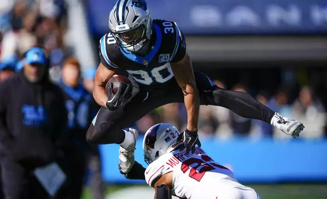 Carolina Panthers running back Chuba Hubbard runs over Arizona Cardinals cornerback Sean Murphy-Bunting during the first half of an NFL football game, Sunday, Dec. 22, 2024, in Charlotte, N.C. (AP Photo/Jacob Kupferman)