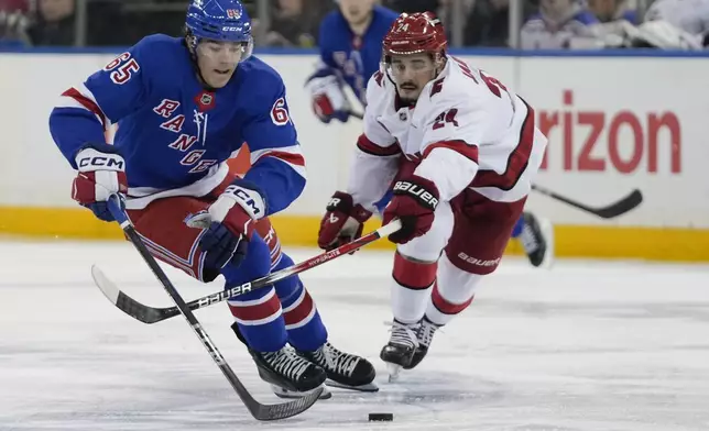 New York Rangers' Brett Berard (65) fights for control of the puck with Carolina Hurricanes' Seth Jarvis (24) during the second period of an NHL hockey game Sunday, Dec. 22, 2024, in New York. (AP Photo/Frank Franklin II)