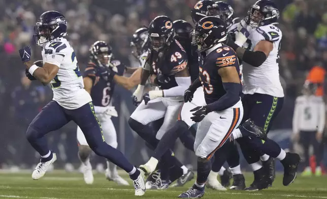 Seattle Seahawks running back Kenny McIntosh, left, runs for yardage against the Chicago Bears during the first half of an NFL football game, Thursday, Dec. 26, 2024, in Chicago. (AP Photo/Nam Y. Huh)