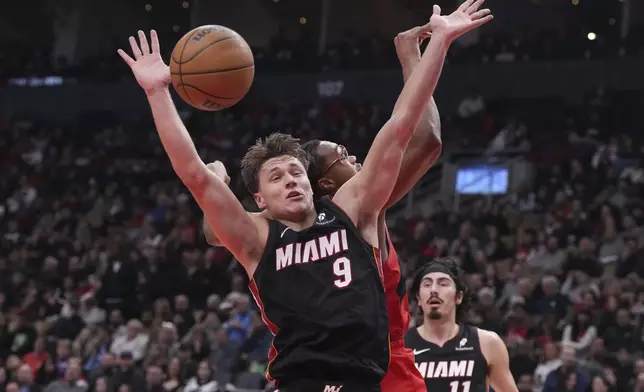 Miami Heat's Pelle Larsson (9) battles for the ball with Toronto Raptors' Scottie Barnes, center right, during first-half NBA basketball game action in Toronto, Sunday, Dec. 1, 2024. (Chris Young/The Canadian Press via AP)