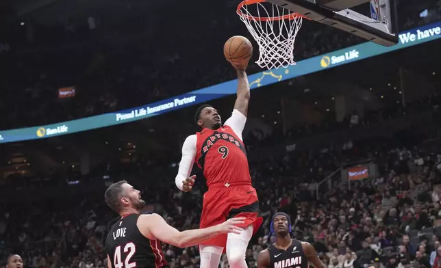 Toronto Raptors' RJ Barrett (9) scores as Miami Heat's Kevin Love (42) and Jimmy Butler (22) watch during first-half NBA basketball game action in Toronto, Sunday, Dec. 1, 2024. (Chris Young/The Canadian Press via AP)