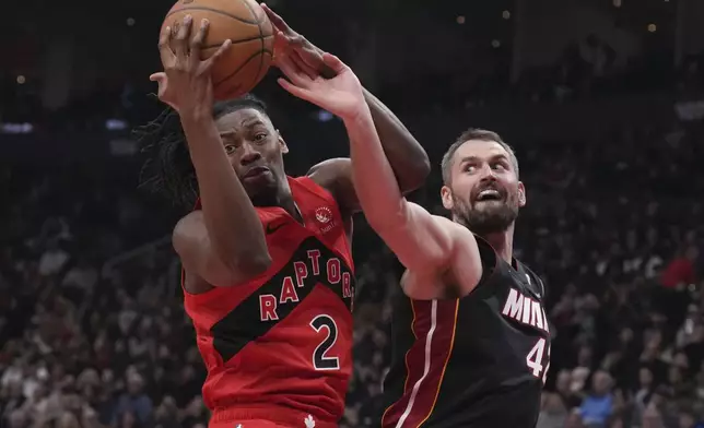 Toronto Raptors' Jonathan Mogbo (2) claims the ball from Miami Heat's Kevin Love, right, during first-half NBA basketball game action in Toronto, Sunday, Dec. 1, 2024. (Chris Young/The Canadian Press via AP)