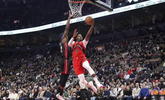 Toronto Raptors' RJ Barrett (9) scores past Miami Heat's Jimmy Butler, center left, during first-half NBA basketball game action in Toronto, Sunday, Dec. 1, 2024. (Chris Young/The Canadian Press via AP)