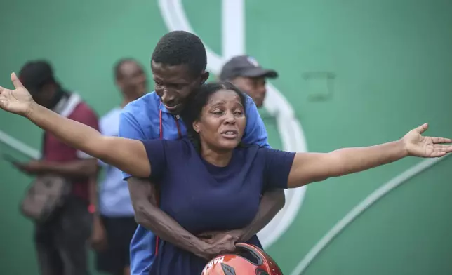 The wife of a journalist, who was shot during an armed gang attack on the General Hospital, cries as an ambulance arrives with his body, at a different hospital in Port-au-Prince, Haiti, Tuesday, Dec. 24, 2024. (AP Photo/Odelyn Joseph)