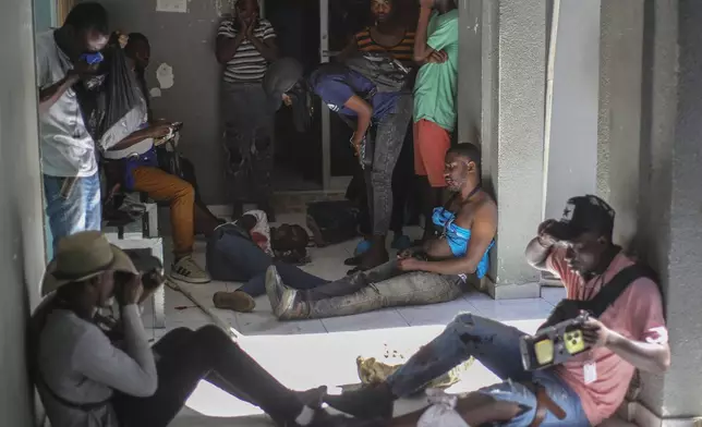 Journalists sit wounded after being shot by armed gangs at the General Hospital in Port-au-Prince, Haiti, Tuesday, Dec. 24, 2024. (AP Photo/Jean Feguens Regala)