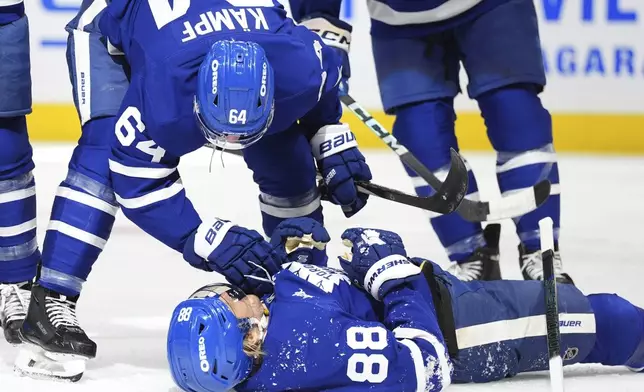 Toronto Maple Leafs center David Kampf (64) celebrates with right wing William Nylander (88) after Nylander scored during second-period NHL hockey game action against the New York Islanders in Toronto, Saturday, Dec. 21, 2024. (Frank Gunn/The Canadian Press via AP)