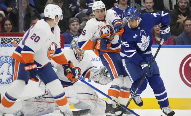 Toronto Maple Leafs right wing Ryan Reaves (75) battles for the puck with New York Islanders defenceman Isaiah George (36) in front of Islanders goaltender Ilya Sorokin (30) during the first period of an NHL hockey game in Toronto, Saturday, Dec. 21, 2024. (Frank Gunn/The Canadian Press via AP)