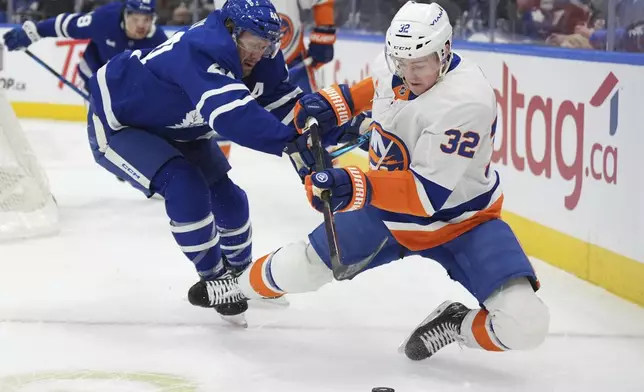 Toronto Maple Leafs defenseman Morgan Rielly (44) and New York Islanders center Kyle MacLean (32) battle for the puck during the first period of an NHL hockey game in Toronto, Saturday, Dec. 21, 2024. (Frank Gunn/The Canadian Press via AP)