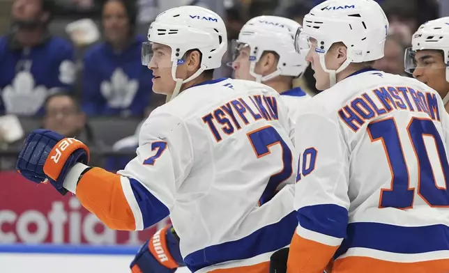 New York Islanders right wing Maxim Tsyplakov (7) celebrates with teammate after scoring on Toronto Maple Leafs goaltender Joseph Woll during the first period of an NHL hockey game in Toronto, Saturday, Dec. 21, 2024. (Frank Gunn/The Canadian Press via AP)