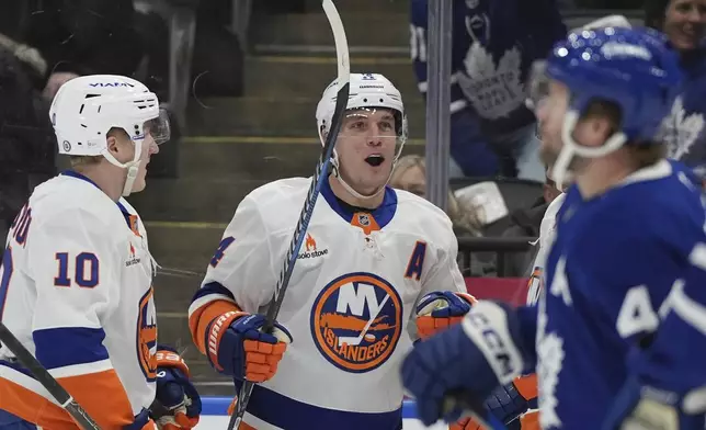 New York Islanders center Bo Horvat, center, celebrates after scoring his team's second goal against Toronto Maple Leafs goaltender Joseph Woll (not shown) during first-period NHL hockey game action in Toronto, Saturday, Dec. 21, 2024. (Frank Gunn/The Canadian Press via AP)