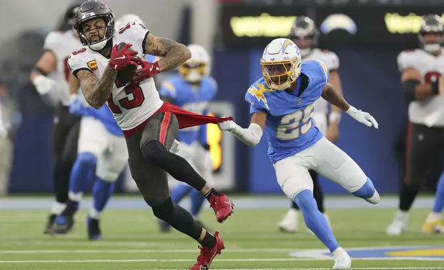 Tampa Bay Buccaneers wide receiver Mike Evans (13) has his shirt pulled by Los Angeles Chargers cornerback Tarheeb Still (29) after a catch during the second half of an NFL football game Sunday, Dec. 15, 2024, in Inglewood, Calif. (AP Photo/Ryan Sun)