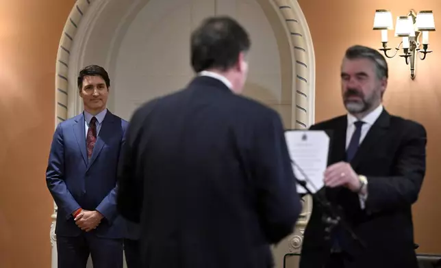 Prime Minister Justin Trudeau, left, looks on as Dominic LeBlanc, center, is sworn in as finance minister by Clerk of the Privy Council John Hannaford, right, during a ceremony at Rideau Hall in Ottawa, Ontario, Monday, Dec. 16, 2024. (Justin Tang/The Canadian Press via AP)