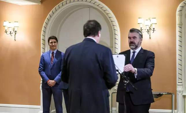 Canada's Prime Minister Justin Trudeau, left, looks on as Dominic LeBlanc, centre, is sworn in as Finance Minister by Clerk of the Privy Council John Hannaford, right, during a ceremony at Rideau Hall in Ottawa, Ontario, Monday, Dec. 16, 2024. (Justin Tang/The Canadian Press via AP)