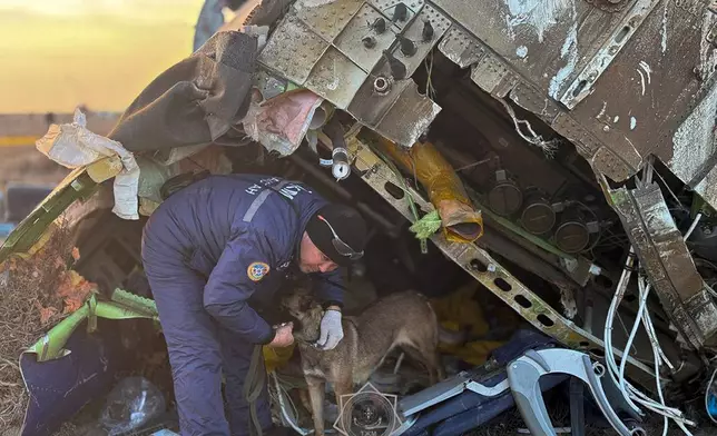 In this photo released by Kazakhstan's Emergency Ministry Press Service, a rescuer search at the wreckage of Azerbaijan Airlines' Embraer 190 laying on the ground near the airport of Aktau, Kazakhstan, Thursday, Dec. 26, 2024. (Kazakhstan's Emergency Ministry Press Service via AP)