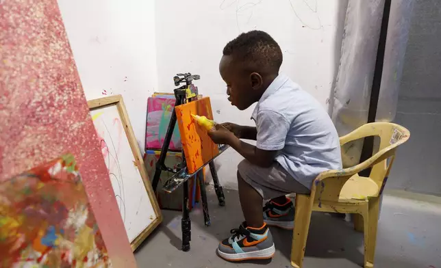 FILE - Ace-Liam Nana Sam Ankrah, who will turn two in July, paints at his mother's art gallery in Accra, Ghana, May 27, 2024. (AP Photo/Misper Apawu, File)