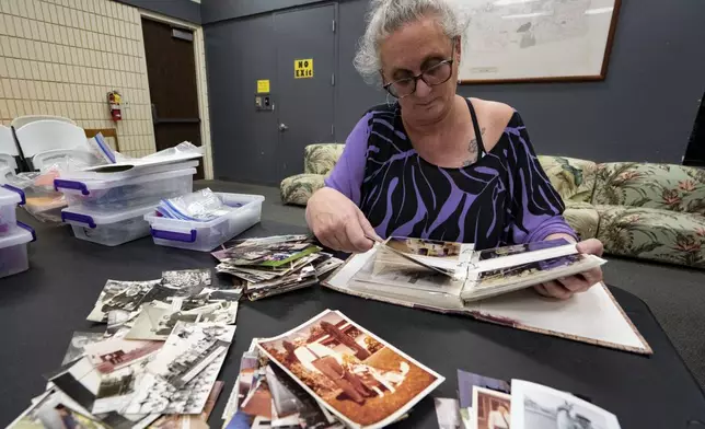 Pam Walton flips through an album containing photographs of “Two by Twos” members and ministers, or “workers,” at a library Monday, Dec. 9, 2024, in Wailea, Hawaii. (AP Photo/Mengshin Lin)