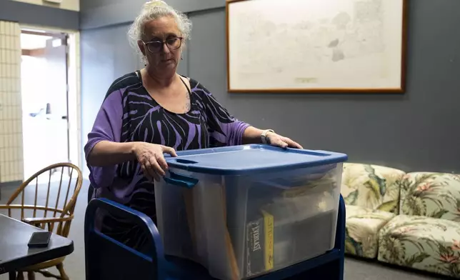 Pam Walton packs her container with the photographs and lists of "Two by Twos" conventions, members and ministers, at a library Monday, Dec. 9, 2024, in Wailea, Hawaii. (AP Photo/Mengshin Lin)