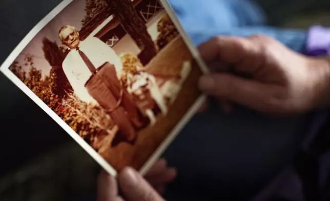 Pam Walton, a former “Two by Twos” sect member who helps track movements of allegedly predatory members through photographs and documents, holds a photograph of a deceased spiritual leader of the sect at a library Monday, Dec. 9, 2024, in Wailea, Hawaii. (AP Photo/Mengshin Lin)